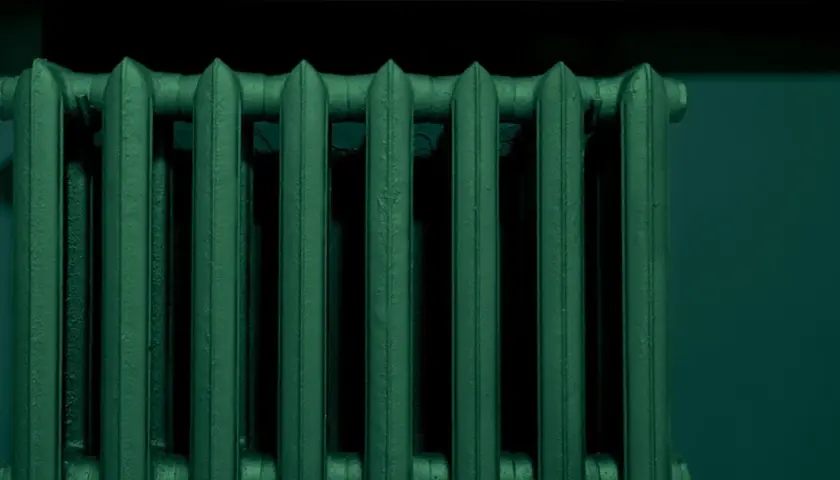 Un termosifone in ghisa, appena verniciato di un verde scuro e profondo, pronto a scaldare l'ambiente.
