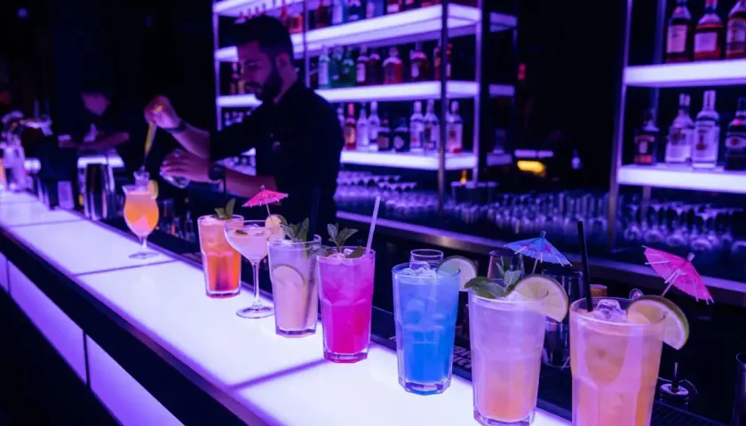 Kolorowe drinki na barze, barman przygotowuje kolejny. Idealne miejsce na relaks i smakowanie wyśmienitego **alkoholu** na **Malcie**.