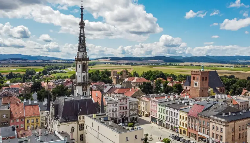 Widok na rynek i wieżę ratuszową w Ząbkowicach Śląskich. W tle pola i góry.