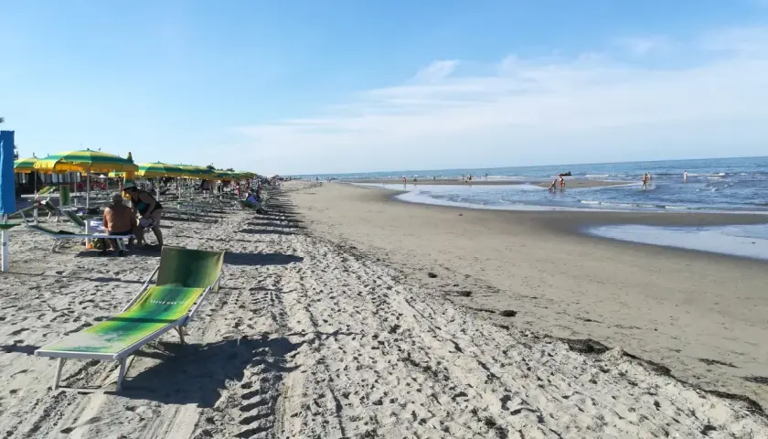 Una giornata di sole sulla spiaggia del Veneto. Ombrelloni colorati, lettini e il mare azzurro invitano al relax.