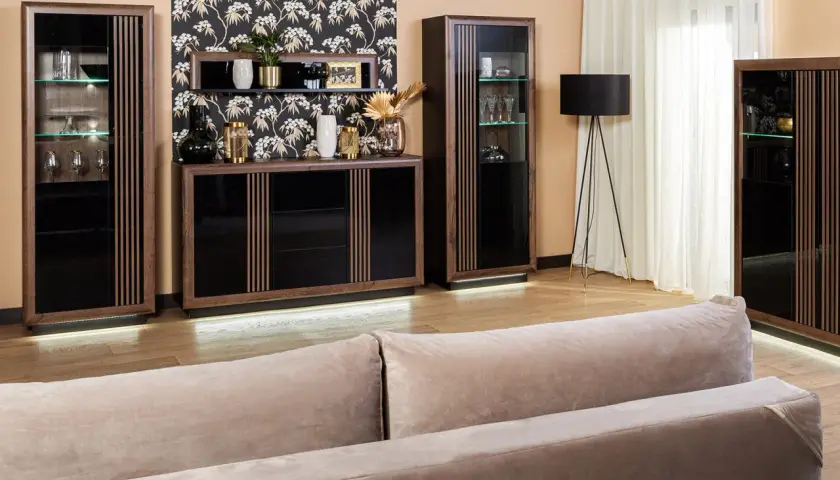 Elegancka komoda i witryny z ciemnego drewna, ozdobione pionowymi lamelkami, tworzą stylowy zestaw mebli.