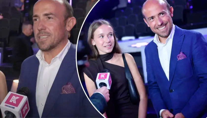 Borys Budka z córką na ściance. Mężczyzna w niebieskiej marynarce, dziewczyna w czarnej sukience.