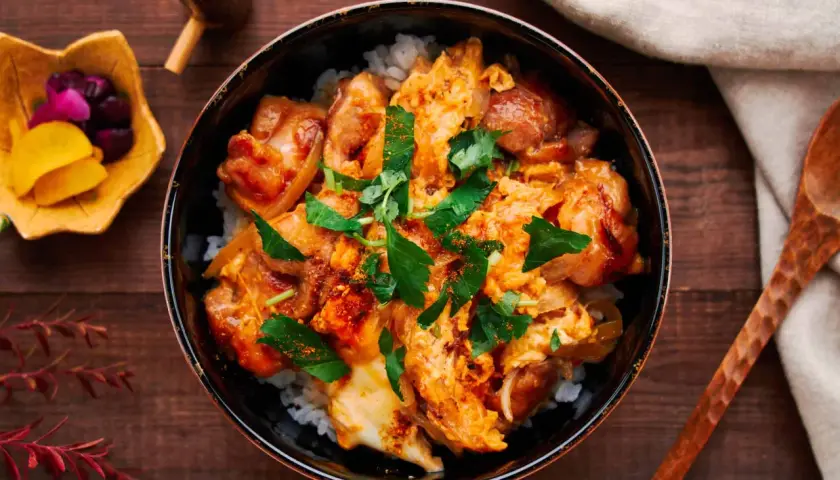 A delicious oyaku donburi recipe, featuring tender chicken and fluffy egg over rice, garnished with fresh parsley.