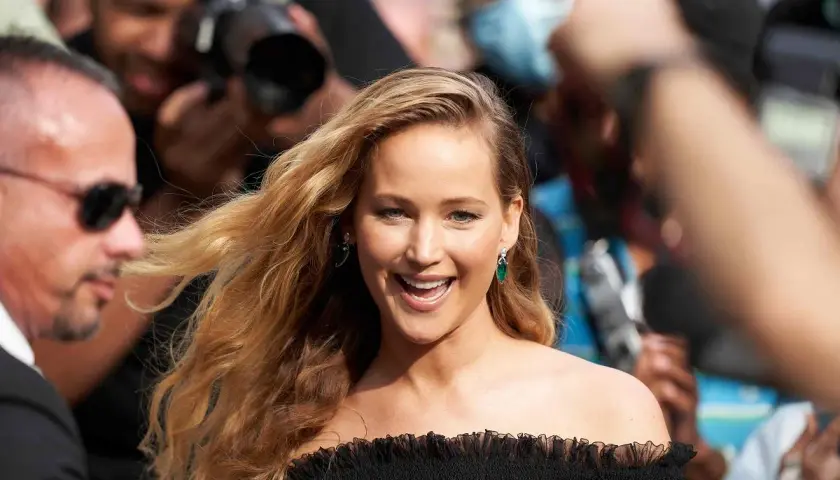 Jennifer Lawrence, uśmiechnięta, otoczona przez paparazzi. Ciekawe, ile lat ma Jennifer Lawrence, gdy robi taką karierę?