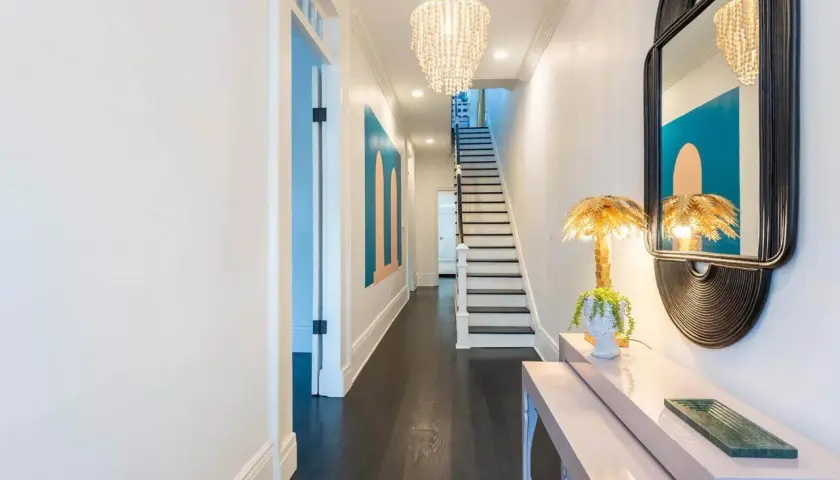 A stylish entryway table styled with a bust planter, palm leaf lamp, and a green tray. This setup offers inspiration on how to style an entryway table.