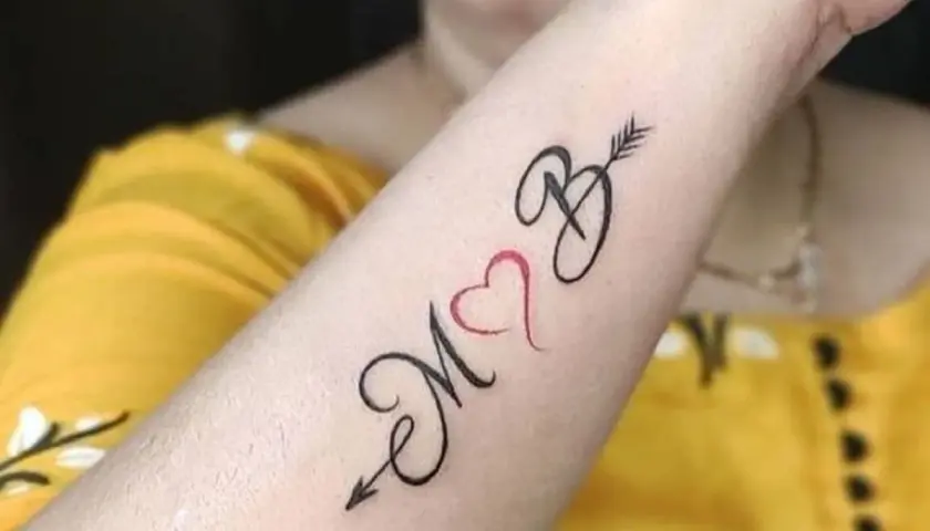 Tatuaż serce z inicjałami M i B, połączone strzałą. Symbol miłości i więzi.