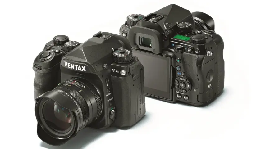 Dwa czarne aparaty Pentax K-1 Mark II z obiektywami, jeden z przodu z szerokokątnym obiektywem, drugi z tyłu, pokazujący ekran i przyciski.