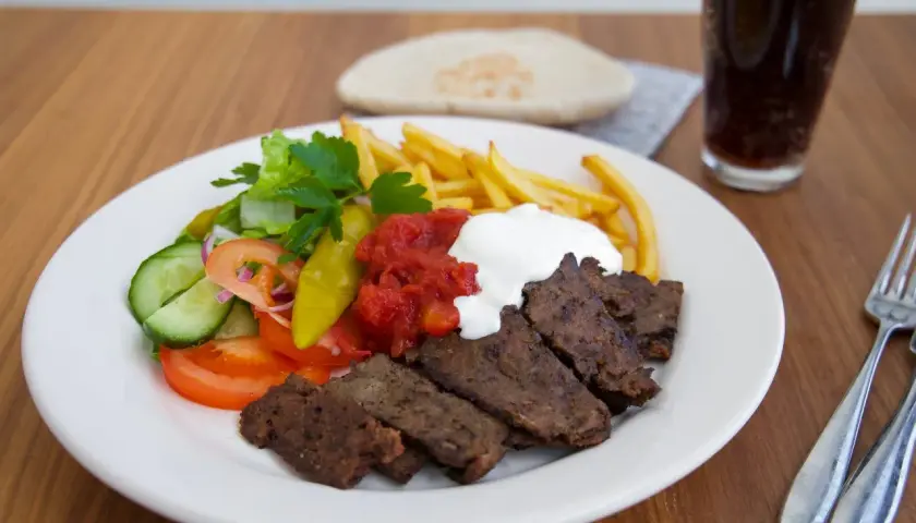En tallrik med turkisk kebab från Zeinas Kitchen, med pommes frites, sallad, tomatsås och vit sås.