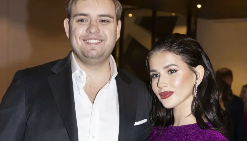 Roksana Węgiel i jej mąż, Kevin Mglej, uśmiechają się do obiektywu. Ona w błyszczącej, fioletowej sukience, on w eleganckim garniturze.