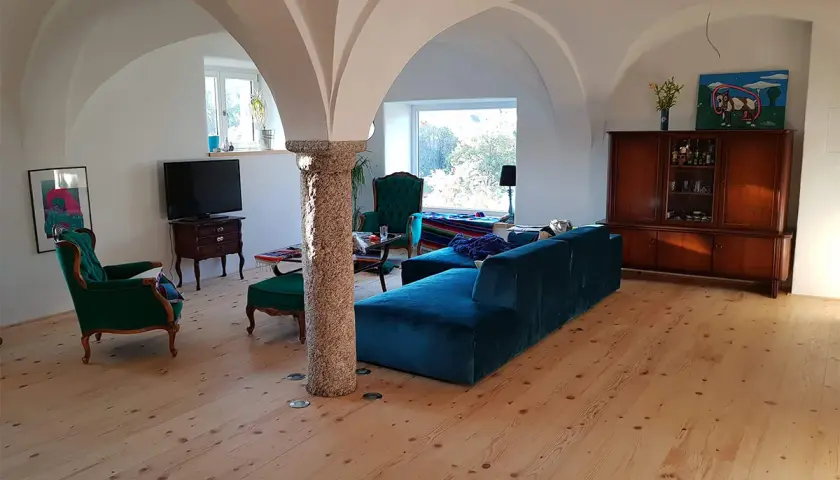 Gemütliches Wohnzimmer mit Gewölbedecke, das zeigt, wie ein alter Stall zu Wohnraum umgebaut wurde. Genehmigung für solche Projekte ist oft nötig.