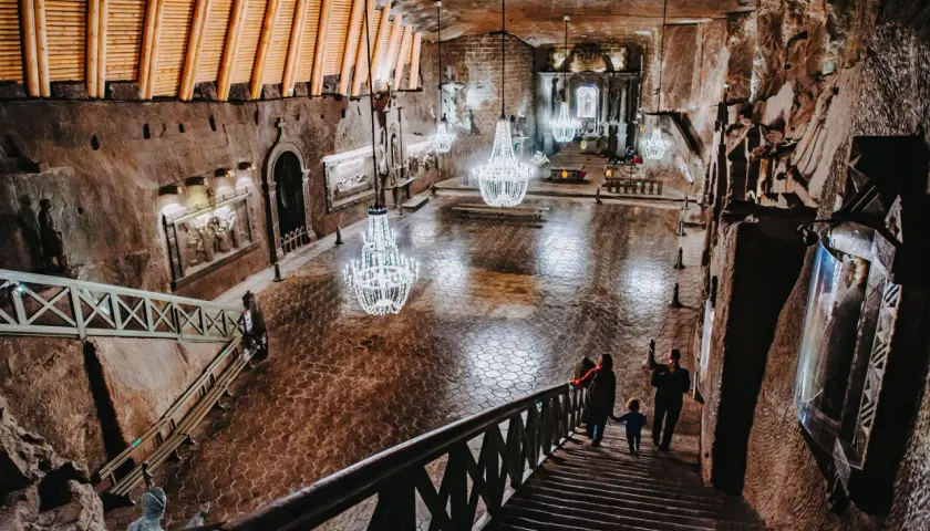 Rodzina schodzi schodami do podziemnej kaplicy w kopalni soli „wieliczka” opinie. Kryształowe żyrandole oświetlają solne rzeźby.