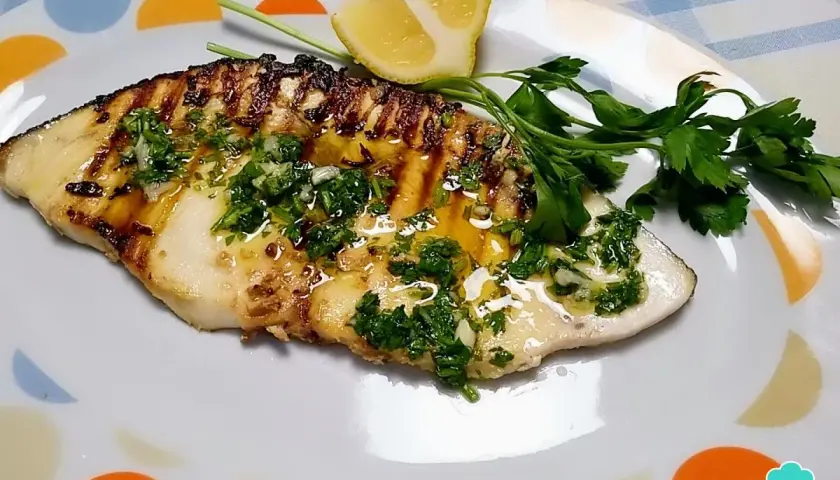Filete de pez espada a la parrilla con perejil picado y limón.