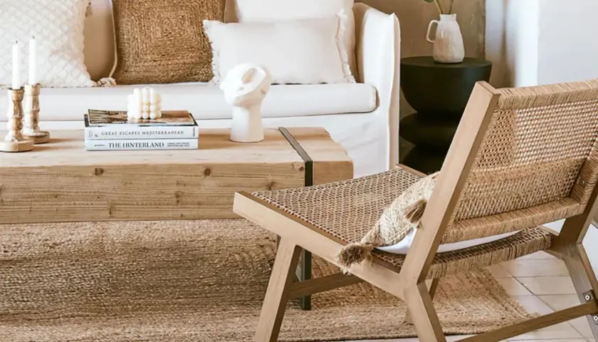 Gemütliches Wohnzimmer im boheme stil mit Rattan-Stuhl, Holztisch und Kissen.