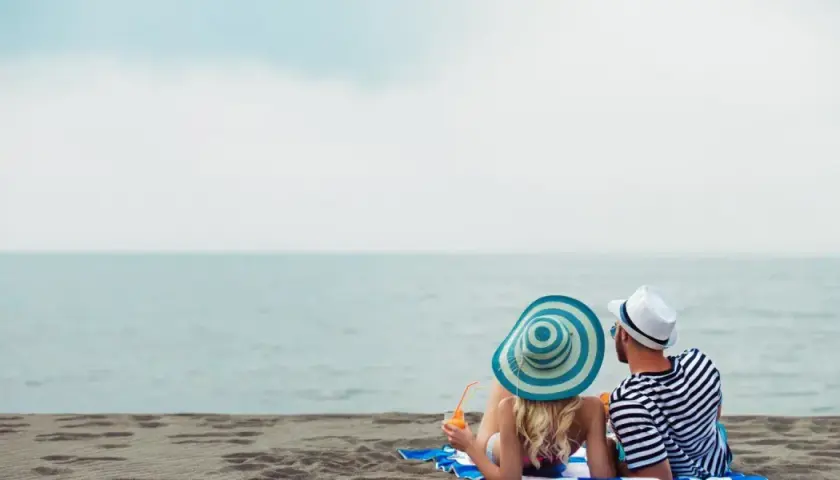 Para relaksu na plaży w Mielnie. Para w kapeluszach popija drinki, ciesząc się widokiem morza. Idealne mielno atrakcje dla dorosłych.