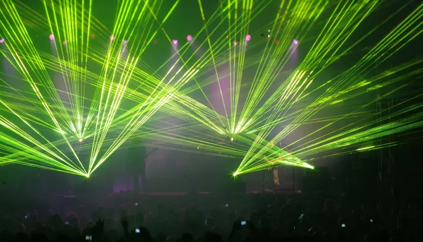 Koncertowe szaleństwo! Zielone lasery rozświetlają scenę, tworząc niesamowitą atmosferę dla zagranicznych legendarnych zespołów rockowych. Tłum szaleje.