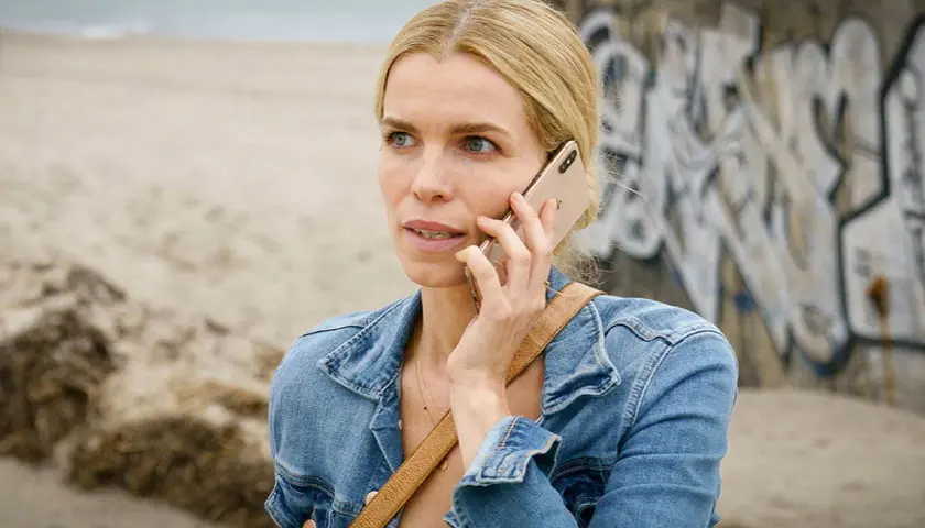 En kvinna i jeansjacka pratar i telefon vid en strand. Kanske en scen från en ny dansk serie på TV4.