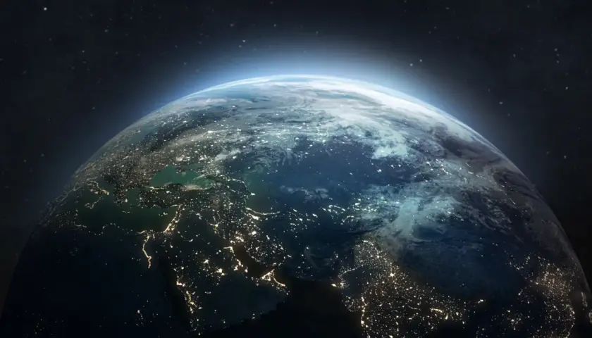 Widok Ziemi z kosmosu nocą, rozświetlonej miastami. W tle gwiazdy i delikatna poświata atmosfery, jakby patrzyły na nią satelity.