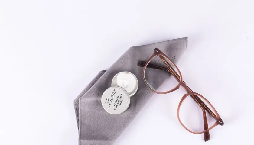Brillenpflege: Acetatstoff waschen und mit Pflegemittel auffrischen. Brille und Tuch liegen bereit.