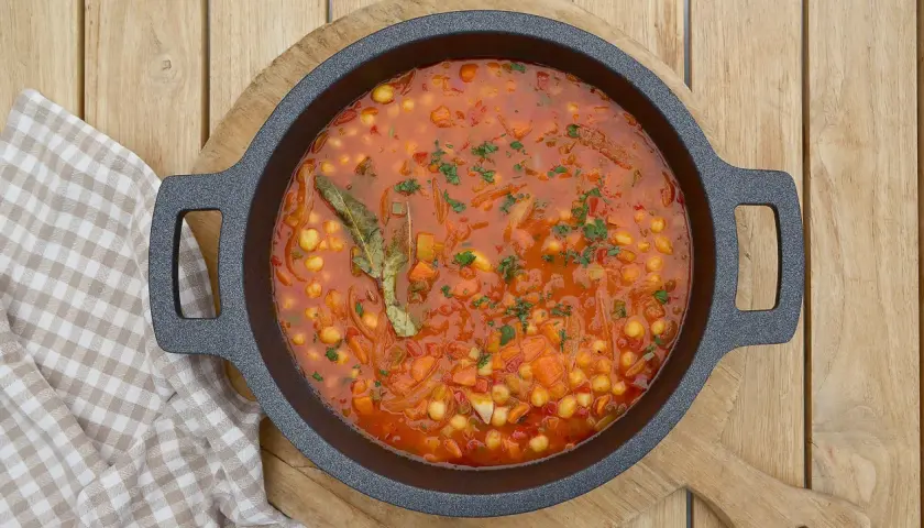 Un plato humeante de garbanzos con verduras, lleno de zanahoria, cebolla y especias, listo para ser disfrutado.