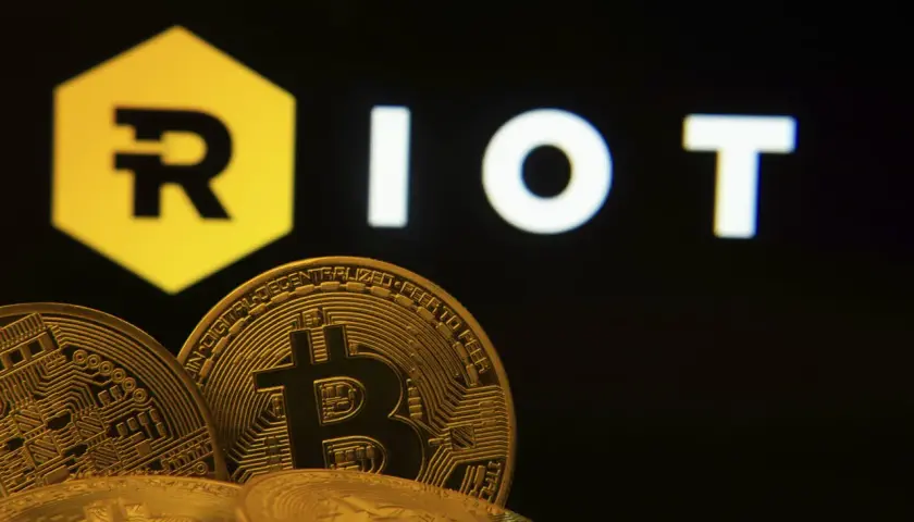 Goldene Bitcoin-Münzen vor dem "RIOT"-Logo. Die Riot Platforms Aktie im Fokus der Kryptowelt.