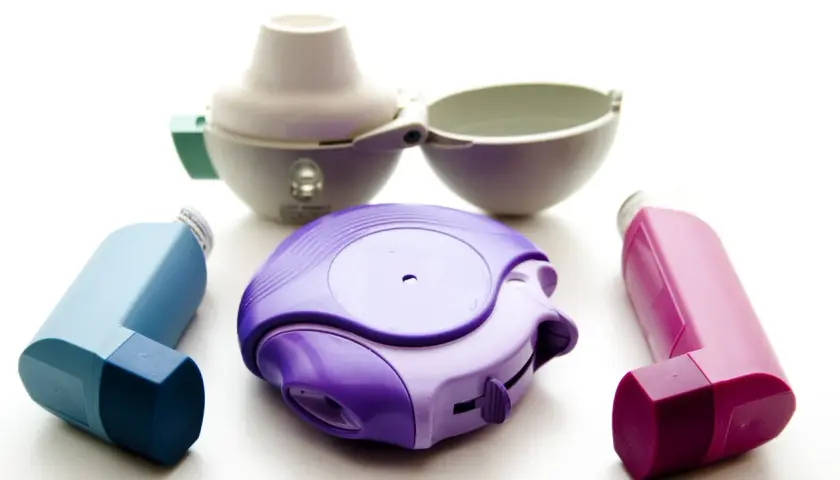Drei Inhalatoren in Lila, Blau und Pink, sowie ein offener weißer Inhalator. Ein Beispiel für Medikamente wie Spiriva.