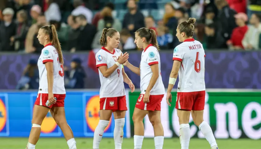 Piłkarki w biało-czerwonych strojach, reprezentujące polskie dania, na boisku.