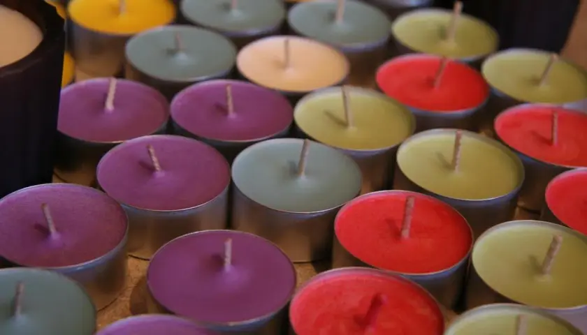 Un surtido de velas no tóxicas de colores vibrantes, dispuestas en filas.