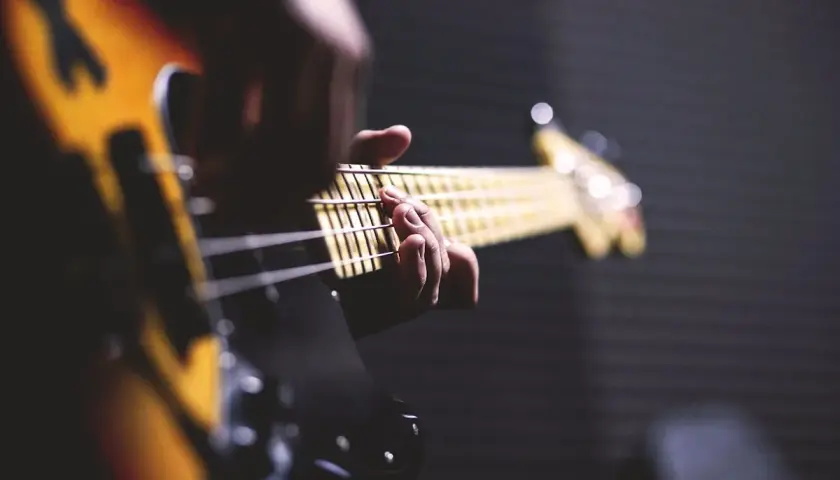 Main d'un bassiste jouant sur une guitare électrique. Parfait pour un texte pour annoncer la sortie d'un single.