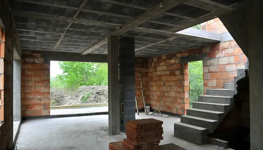 Wnętrze budowanego domu szeregowego z cegły, betonowym stropem i schodami.