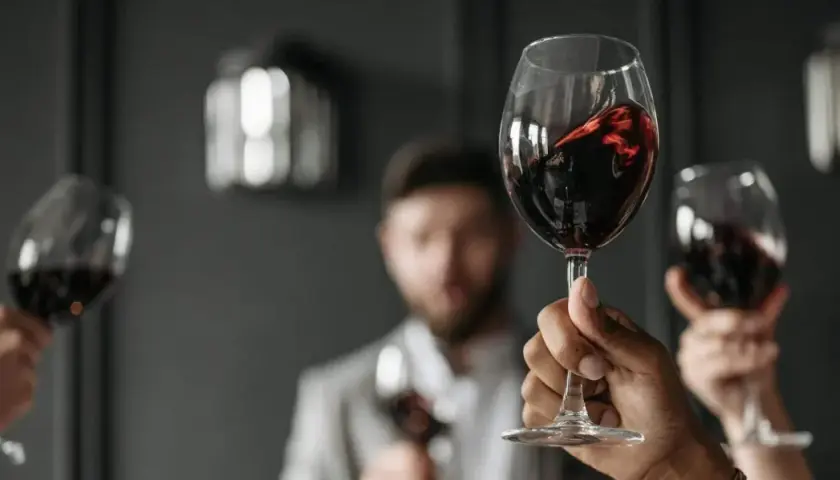 Verre de vin rouge, parfait pour accompagner un foie gras. Des mains lèvent des verres pour un toast.