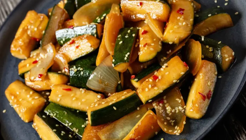 Smażona cukinia z cebulą i sezamem, posypana płatkami chili. Świetny pomysł, co ugotować z cukini, gdy masz jej dużo!