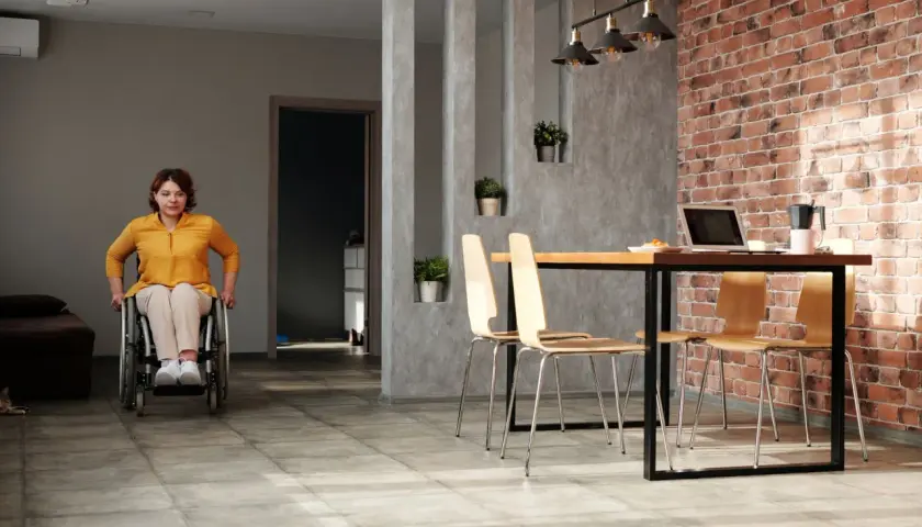 Kobieta na wózku inwalidzkim w swoim mieszkaniu. Czy osoba po udarze może mieszkać sama? Tak, jeśli przestrzeń jest dostosowana.
