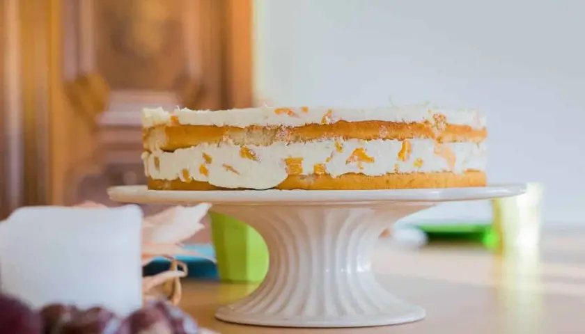 Ein leckerer no bake kuchen mit Sahne und Fruchtstücken auf einem Tortenständer.