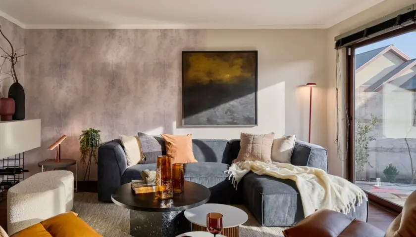 Sofá gris, mesas de centro, sillones de cuero y detalles decorativos. Los **colores que dan luz y amplitud** crean un ambiente acogedor y moderno.