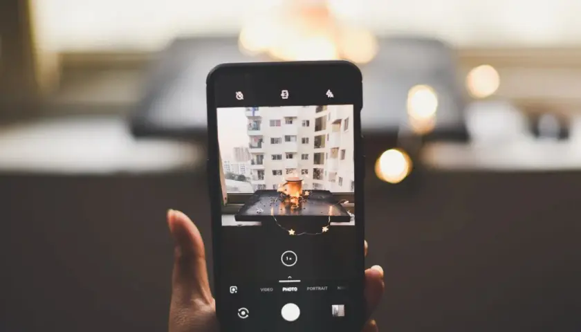 Smartfon robi zdjęcie kubka z napojem i światełek. To przykład fotografii produktowej.