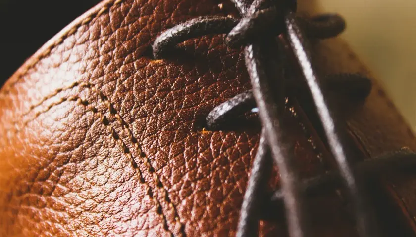 Gros plan sur le cuir texturé d'une chaussure marron, avec des lacets sombres. Un peu de cirage pour chaussures pourrait lui redonner tout son éclat.