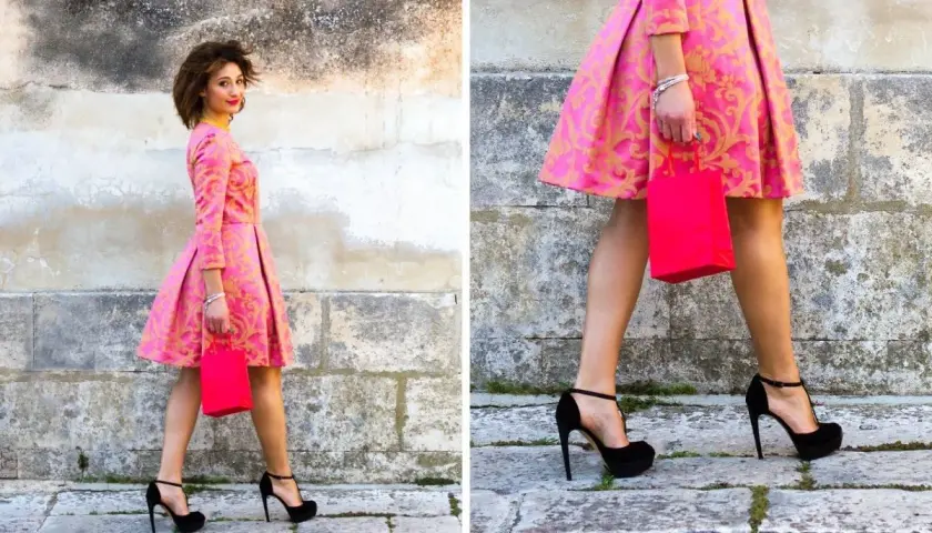 Elegancka kobieta w różowej sukience z złotym wzorem i czarnymi szpilkami. Idealne buty do różowej sukienki na specjalne okazje.