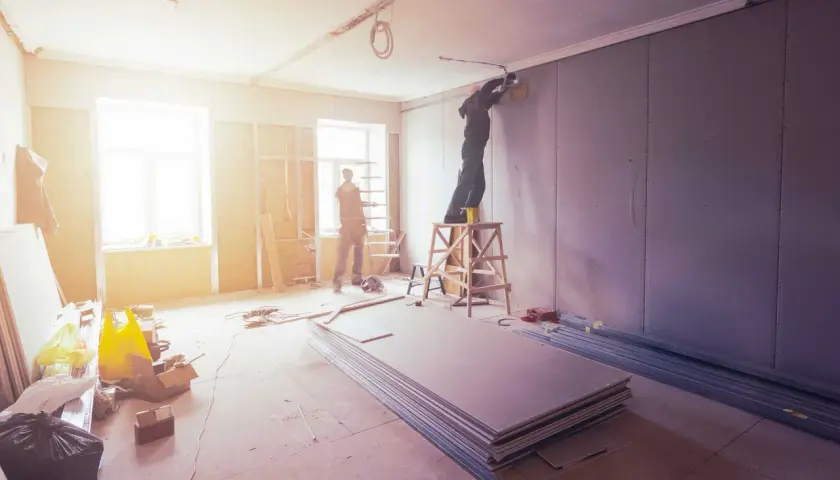 Lavori in corso: operai installano cartongesso. Per sapere quanto costa smaltire il cartongesso, informati sui costi di smaltimento dei materiali edili.