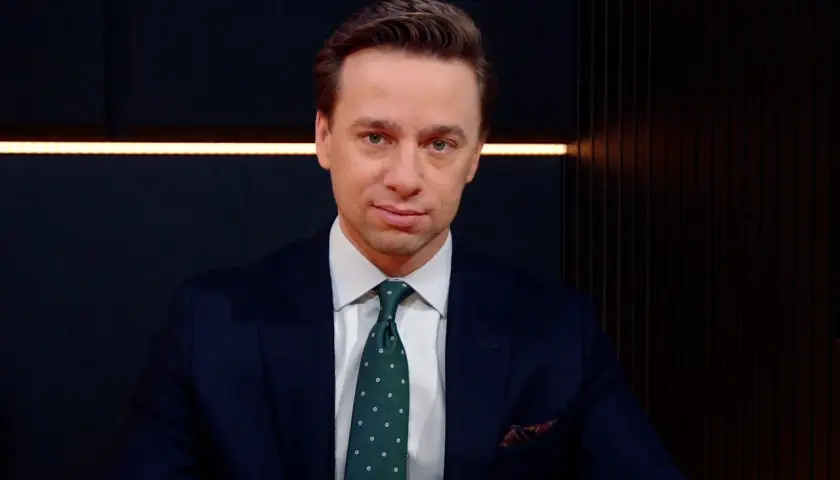 Krzysztof Bosak w garniturze, z zielonym krawatem w kropki. Mówi o tym, dlaczego uważa, że polska polityka zagraniczna nie jest asertywna.