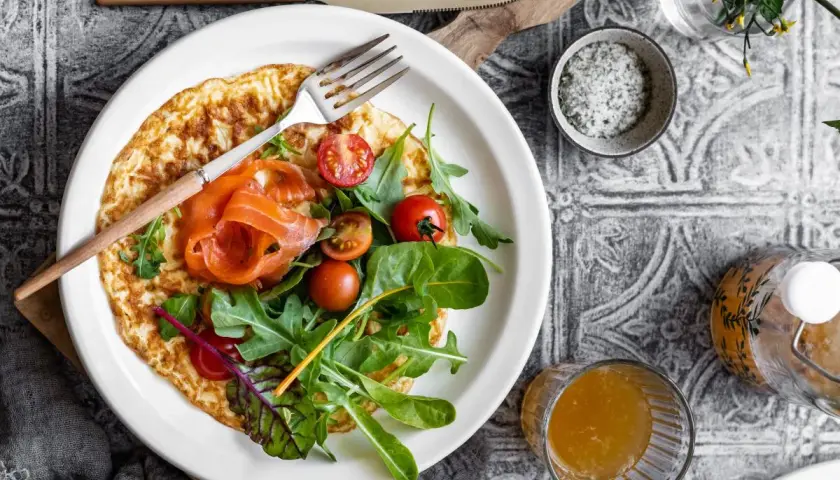 Pyszny omlet na słono z łososiem, pomidorkami i rukolą. Idealny na śniadanie lub lekki lunch.