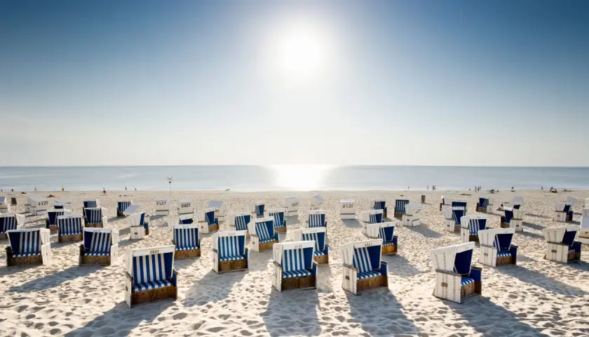 Strandkörbe am Nordseestrand, perfekt für einen entspannten Tagesausflug an die Nordsee. Die Sonne scheint, das Meer glitzert.