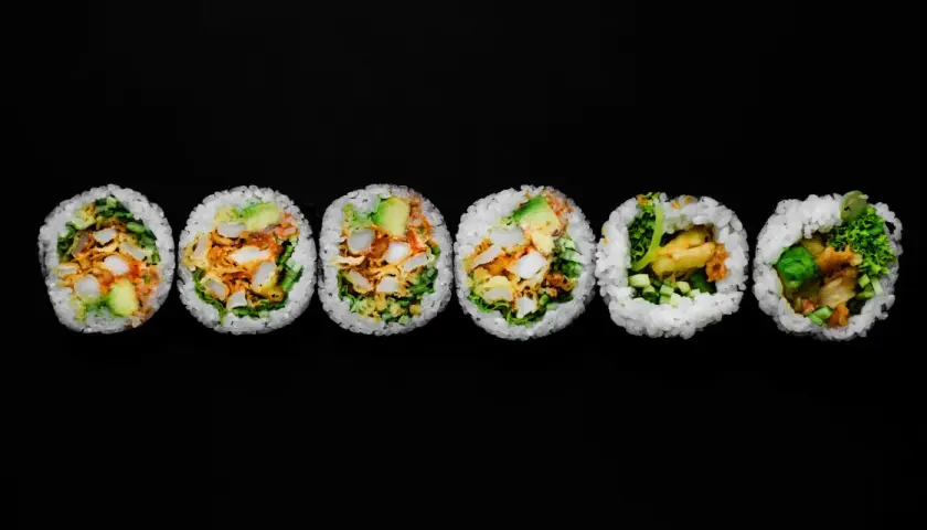 Sześć kawałków futomaki, czyli dużych rolek sushi, z awokado, warzywami i smażonymi kawałkami.