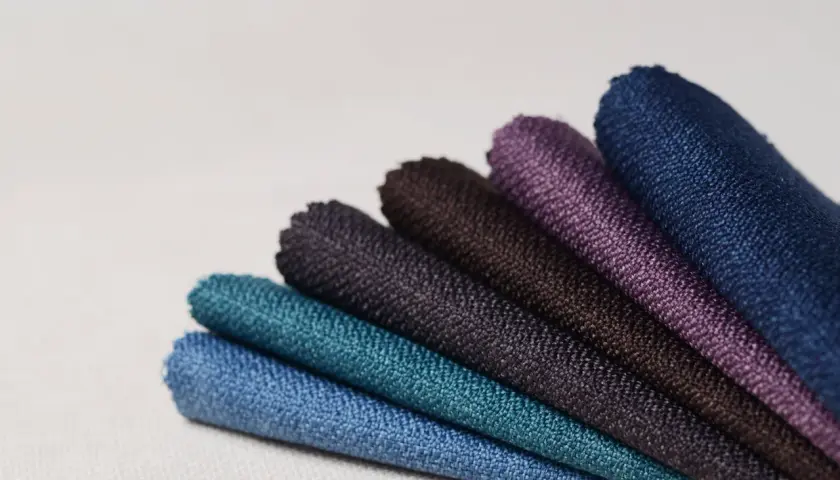 Échantillons de tissus aux teintes profondes, évoquant la richesse des 15 fibres naturelles. Bleu, turquoise, violet, marron.