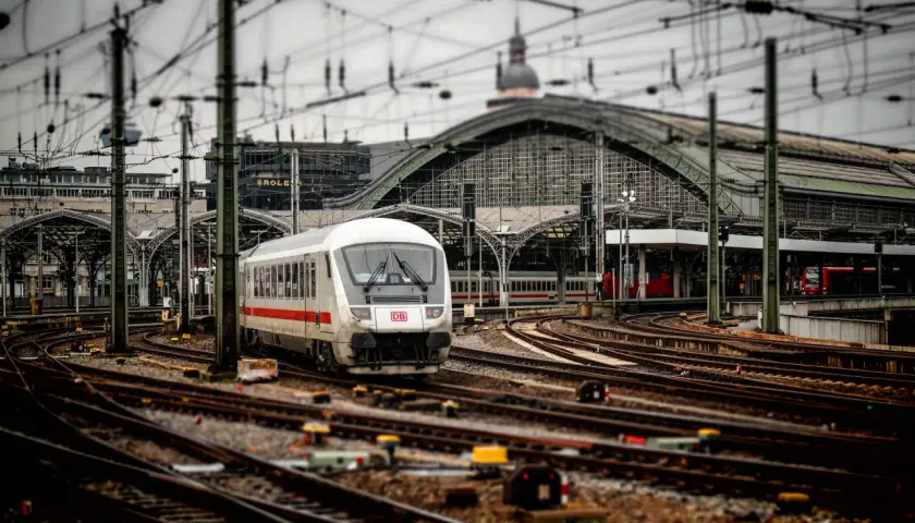 Pociąg DB na stacji, skomplikowana sieć torów i trakcji elektrycznej. Widoczna blokada liniowa sygnalizuje gotowość do odjazdu.