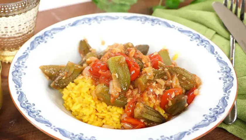 En skål med okra och tomater över gul ris. Ett enkelt okra recept som ser utsökt ut.