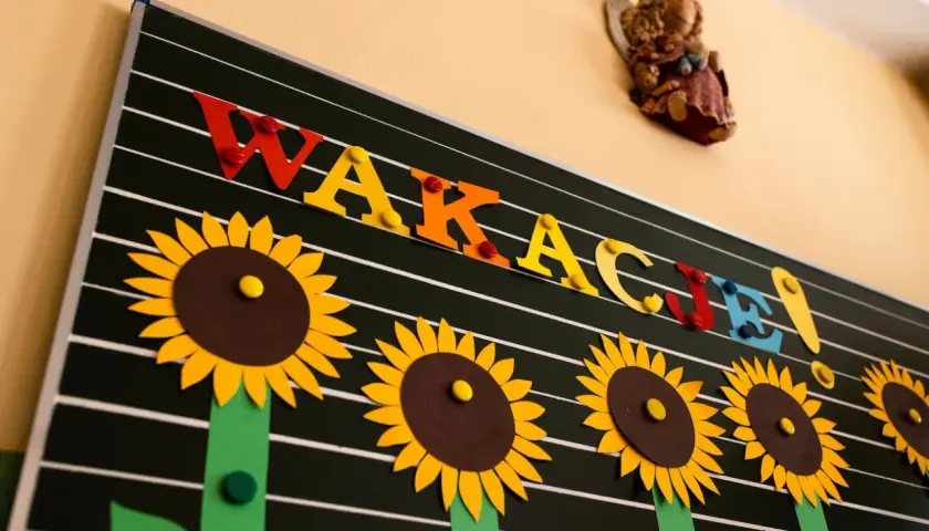 Tablica z napisem "WAKACJE!" ozdobiona słonecznikami.