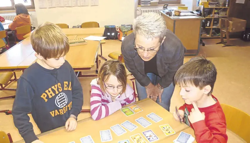 Lehrerin erklärt Kindern beim Projekttag Grundschule ein Kartenspiel.