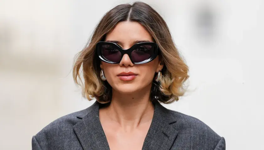 Mujer con gafas de sol y un moderno balayage pelo corto en tonos miel y castaño.
