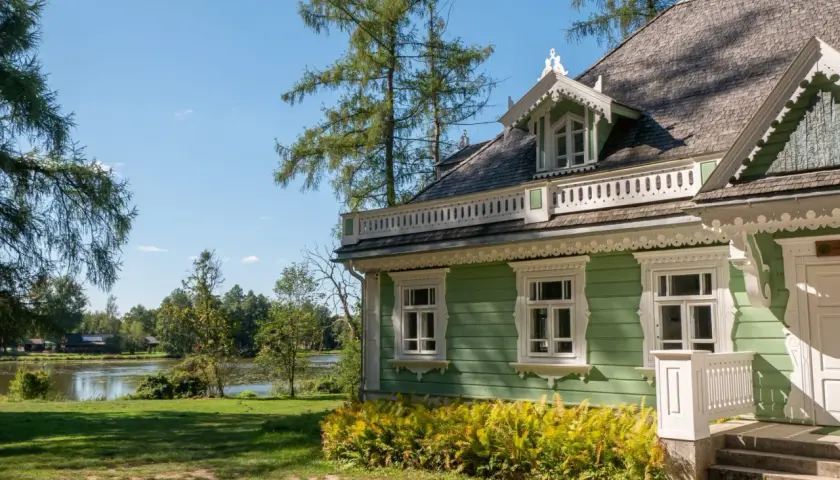 Zielony domek z werandą i ozdobnymi detalami, nad jeziorem. Idealne miejsce na białowieża plan zwiedzania.
