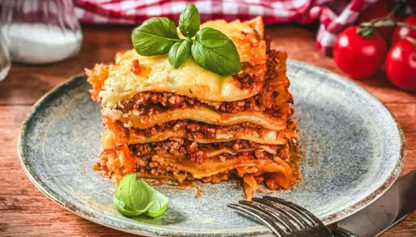 Ein Stück Lasagne Bolognese, ein authentisches lasagne rezept original italienisch, garniert mit Basilikum.